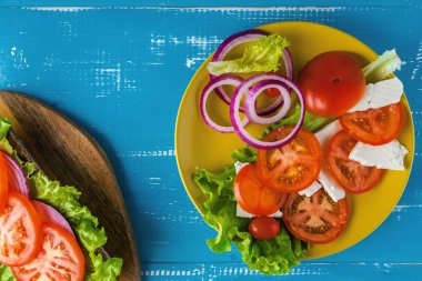 Mavi ahşap arka plan üzerinde salata ile Kahvaltı domates sandviç.