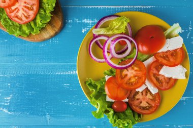 Mavi ahşap arka plan üzerinde salata ile Kahvaltı domates sandviç.