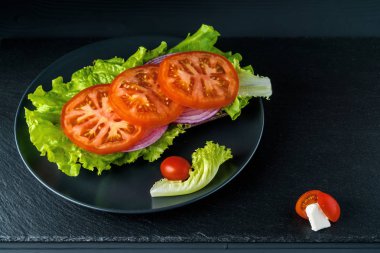 Siyah taş arka plan üzerinde salata ile Kahvaltı domates sandviç.