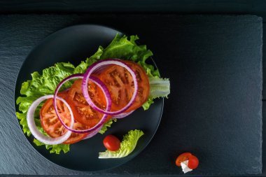 Siyah taş arka plan üzerinde salata ile Kahvaltı domates sandviç.
