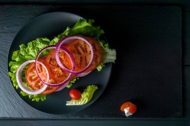 Siyah taş arka plan üzerinde salata ile Kahvaltı domates sandviç.