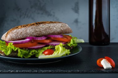 Siyah taş arka plan üzerinde salata ile Kahvaltı domates sandviç.