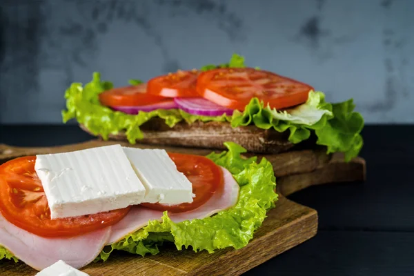 Desayuno sándwich de tomate con ensalada sobre fondo de madera negra . — Foto de Stock