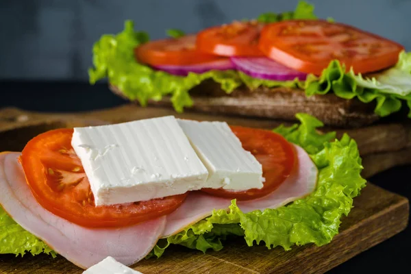 Desayuno sándwich de tomate con ensalada sobre fondo de madera negra . — Foto de Stock