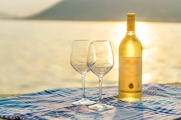 Vista al atardecer de dos copas de vino y botella de vino blanco en el — Foto de Stock