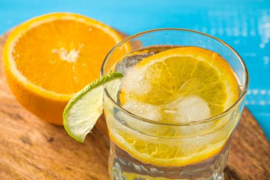 Soğuk yaz kireç ve buzlu lezzetli kuyruk beyaz ve mavi arkaplanda damla damlatan bir bardak.