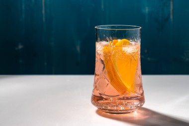 Soğuk yaz kireç ve buzlu lezzetli kuyruk beyaz ve mavi arkaplanda damla damlatan bir bardak.