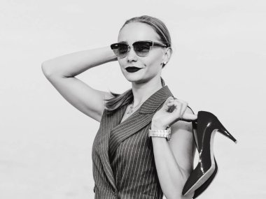 Şık beyaz genç kadının elleri açık parlak yüksek topuklu ayakkabı ile ayakta elbiseli, güneş gözlüğü, tek renkli portre 