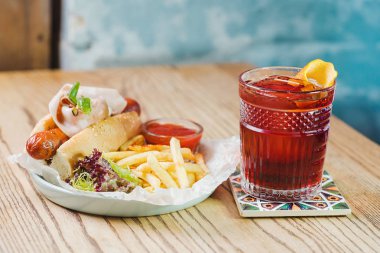 Sosisli sandviç sosis ve jambon, domates sosu ketçap ile ile plaka ve Fransız kızarmış ve masada kokteyl 