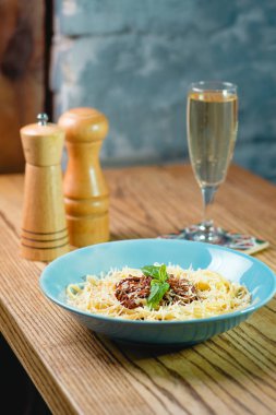 Makarna bolognese plaka, tuz ve biber, masanın üzerine kuru köpüklü şarap