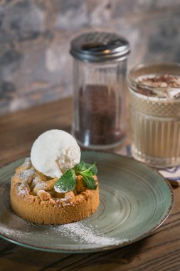 Elmalı turta, üzerinde dondurma, tabakta nane ve masada beyaz kremalı kokteyl.