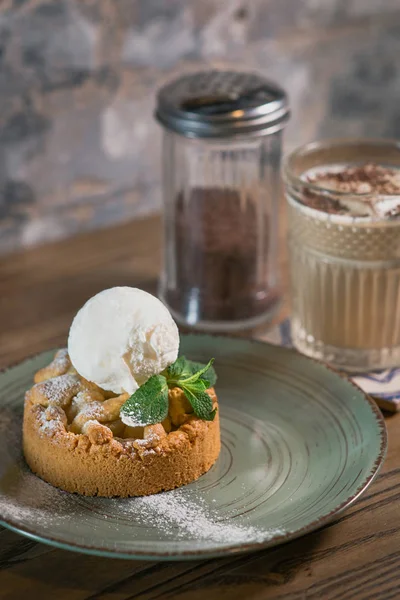Elmalı turta, üzerinde dondurma, tabakta nane ve masada beyaz kremalı kokteyl.