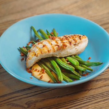 kızarmış tavuk, sos ve yeşil fasulye masada mavi plaka üzerinde