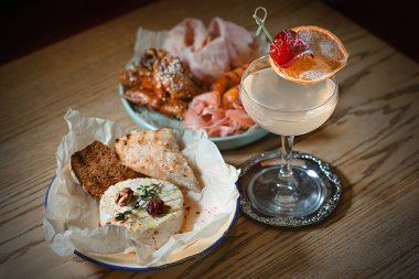 sosis, jambon, jamon ve pişmiş camembert peyniri ve portakal ve vişne tarafından dekore edilmiş alkol kokteyl ile iştah açıcı et tabağı