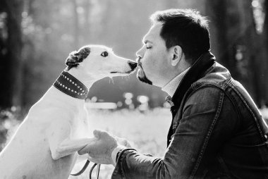 Güzel bir çiftin tek renkli resmi (kadın ve erkek) kot elbiseli, dışarıda köpekleri öpen. Arkadaşlık, aile ve sağlıklı yaşam tarzı kavramı.