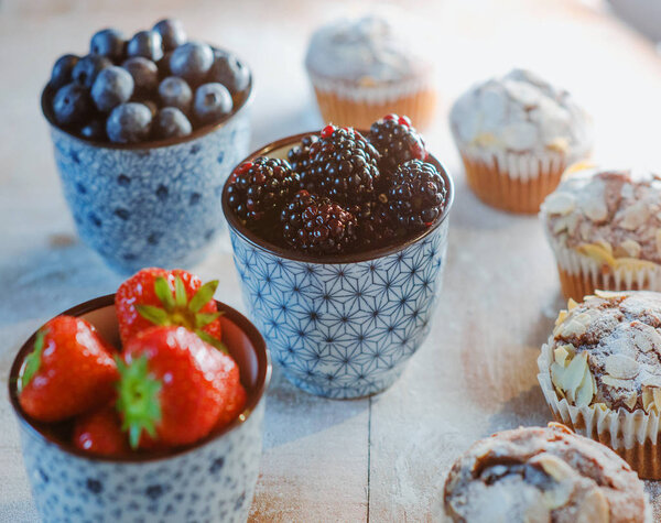 strawberry, blackberry, blueberry and muffins on the table