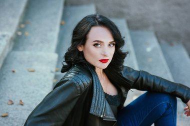 deri ceket ve kot açık merdivenlerde oturan esmer kadın portresi