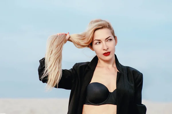 long blonde hair stylish, amazing, fashionable, modern white woman in black bra and suit outdoor in desert