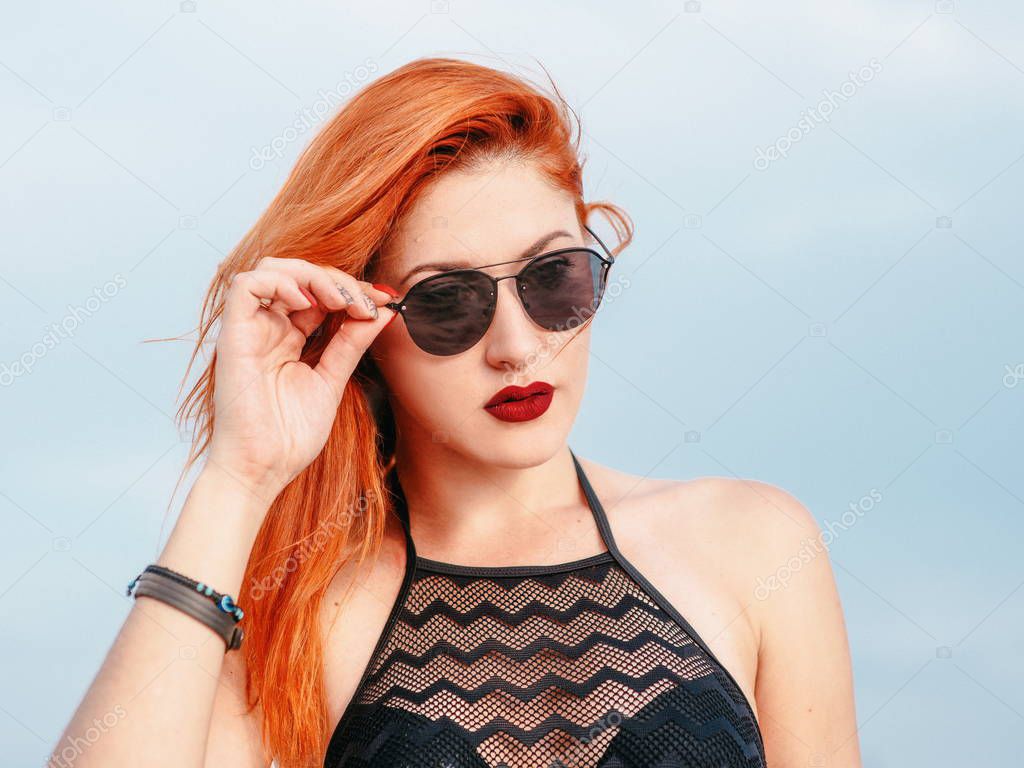 portrait of stylish adorable redhead white lady in sunglasses in desert