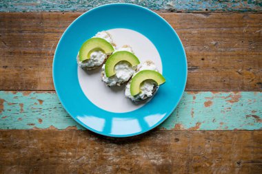 sandviç: krem peynir ve masanın üzerine plaka üzerinde avokado ile tohum ile sağlıklı ekmek