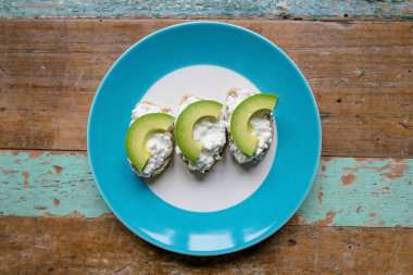 sandviç: krem peynir ve masanın üzerine plaka üzerinde avokado ile tohum ile sağlıklı ekmek