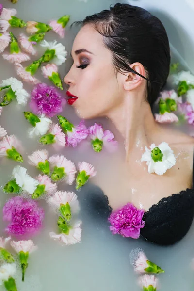 美丽的性感悲伤年轻苗条的黑发妇女在水疗中心 浴室与水和鲜花 — 图库照片