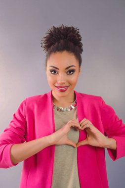 güzel çekici neşeli gülümseyen genç kadın (karışık rase) kalp ellerini tutarak ve aşkını gösterilen