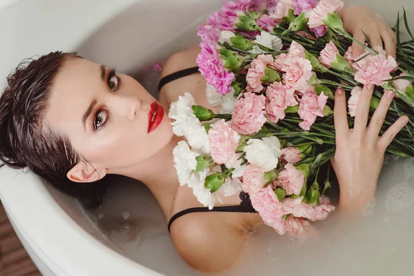 美丽的性感悲伤年轻苗条的黑发妇女在浴室水疗中心与康乃馨花 — 图库照片