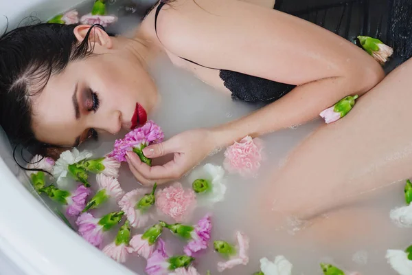 美丽的性感悲伤年轻苗条的黑发妇女在水疗中心 浴室与水和鲜花 — 图库照片