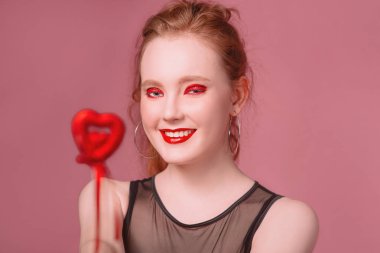 küpe ve ile güzel çekici şık gülen genç Kızıl saçlı kadın portresi makyaj saint valentine's day dekorasyon (kupa) ile onun elinde tonlama yaşam mercan ile