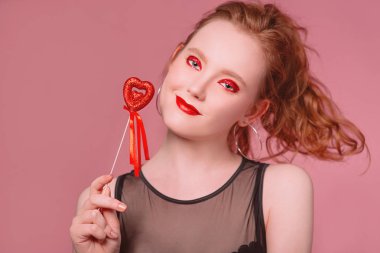 küpe ve ile güzel çekici şık gülen genç Kızıl saçlı kadın portresi makyaj saint valentine's day dekorasyon (kupa) ile onun elinde tonlama yaşam mercan ile