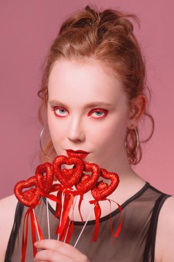 güzel çekici şık genç Kızıl saçlı kadın portresi makyaj saint valentine's day dekorasyon (kupa) ile onun elinde tonlama yaşam mercan ile