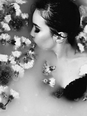 güzel seksi üzgün genç ince esmer kadın banyoda su ve çiçeklerle tek renkli film portresi