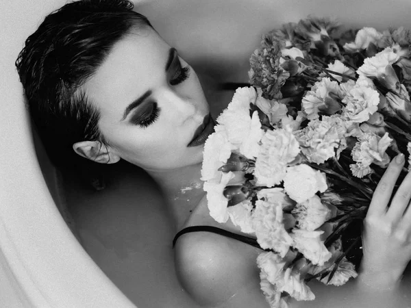 美しいセクシーな悲しいスリム ブルネットの若い女性浴室水と花の白黒フィルムの肖像画 — ストック写真