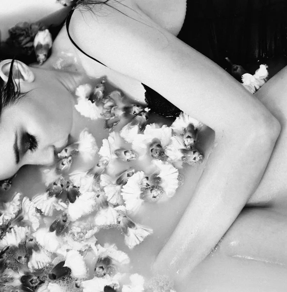 美しいセクシーな悲しいスリム ブルネットの若い女性浴室水と花の白黒フィルムの肖像画 — ストック写真