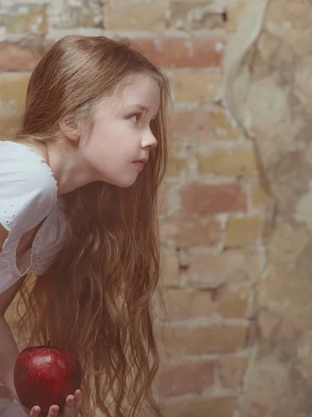 Серйозна Маленька Дівчинка Білій Сукні Червоним Великим Яблуком Фоні Стіни — стокове фото