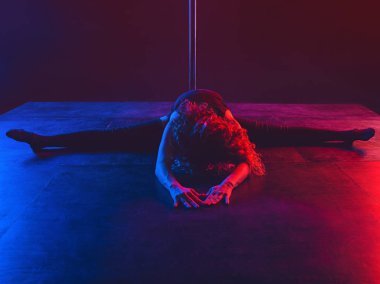 Pole spor: güzel genç atletik fit siyah t-shirt güçlü kızıl saçlı kadın jimnastikçi, şort ve kırmızı çorap spor egzersizleri yapıyor (eğitim, egzersiz) koyu arka plan üzerinde kutup üzerinde