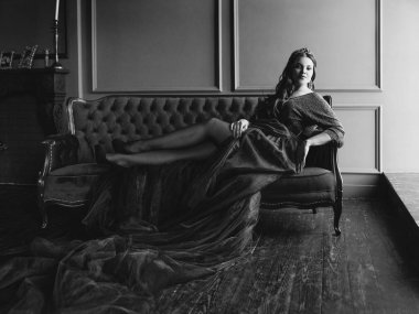 uzun saçlı uzun mor kraliçe elbise ve taç güzel genç güzel sevimli kadın prenses (kraliçe) portresi ve minimalist iç kapalı mavi kadife kanepede oturan makyaj