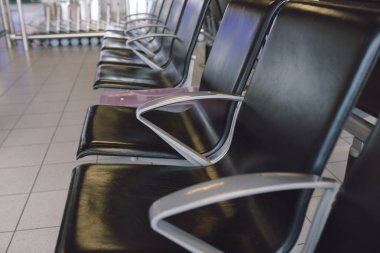 Havaalanının kapısı yakınındaki halka açık alanda siyah boş sandalyeler.