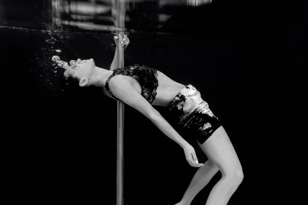 黒い背景のスイミングプールでポールを持つ若い フィット スリムな女性のモノクロの肖像画 — ストック写真