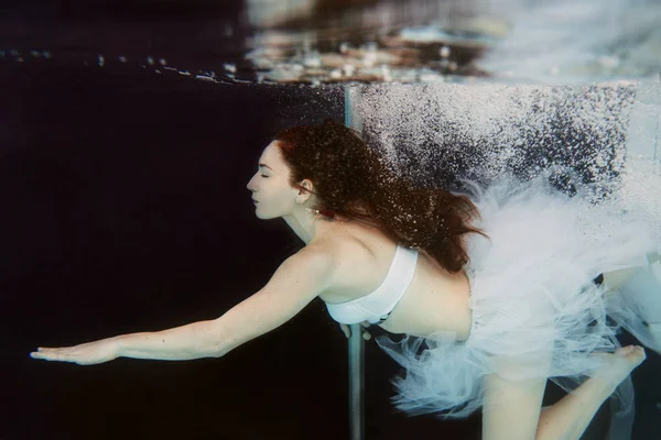 若いです フィット 黒の背景にスイミングプールで水中ポールと白いドレスのスリム女性 — ストック写真
