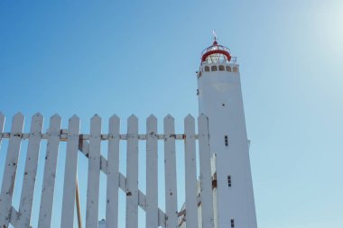 deniz yakınındaki mavi gökyüzü arka planda beyaz çit ile beyaz deniz feneri 