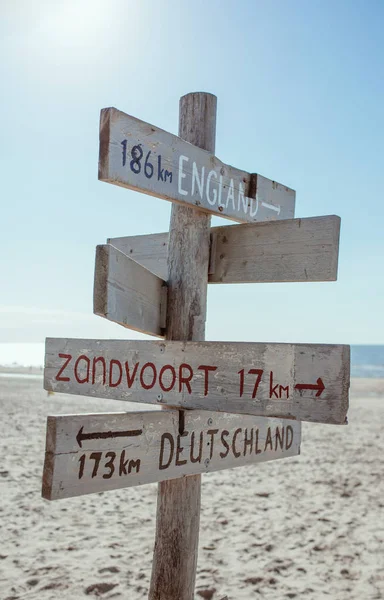 Wooden information board with distance to England, Germany and Zandvoort on the beach by the North Sea in Noordwijk, The Netherlands