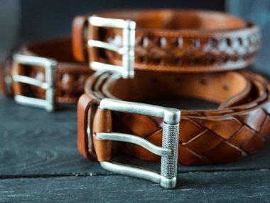 koyu ahşap arka planda üç deri kahverengi kemer