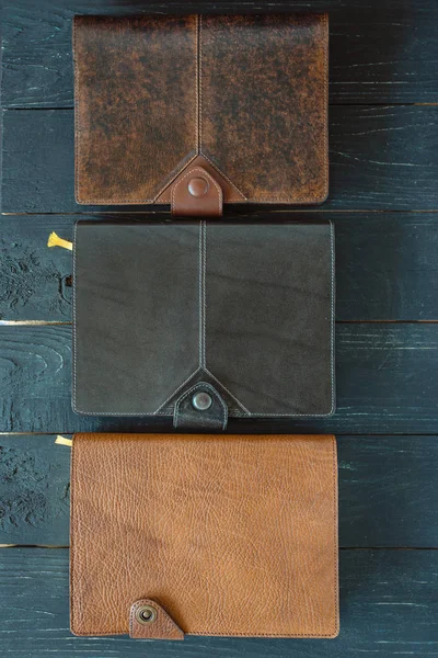 three leather handmade notebooks (organizer) on dark wooden background