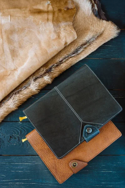 two leather handmade notebooks (organizer) on dark woodenon and leather and fur background