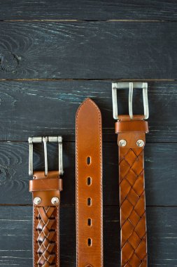koyu ahşap arka planda üç deri kahverengi kemer