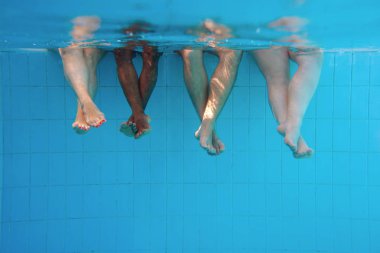 yüzme havuzunda dört kişi ayak lar su altında. Arkadaşlar. Parti. Yaz. Tatil ve spor konsepti.