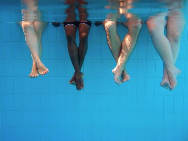 yüzme havuzunda dört kişi ayak lar su altında. Arkadaşlar. Parti. Yaz. Tatil ve spor konsepti.