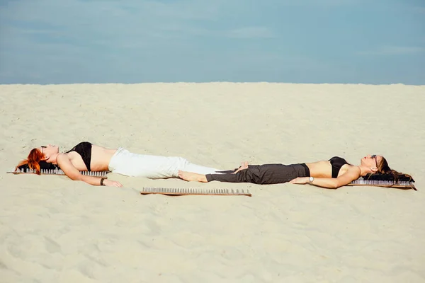 extreme yoga relaxation and self-development - beautiful women laying nacked back on the board with nails in desert outdoor